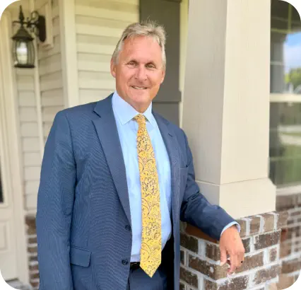 Portrait of William G. Causey, Jr. in a suit standing in front of his office building.