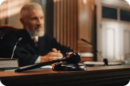A judge in a black robe sits in court holding a gavel